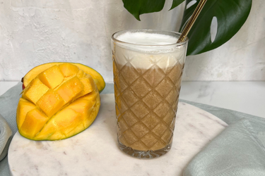 Mango-Eiskaffee in einem Glas, Mango aufgeschnitten daneben