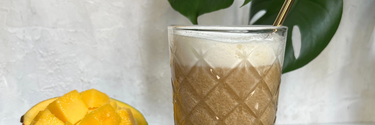 Mango-Eiskaffee in einem Glas, Mango aufgeschnitten daneben