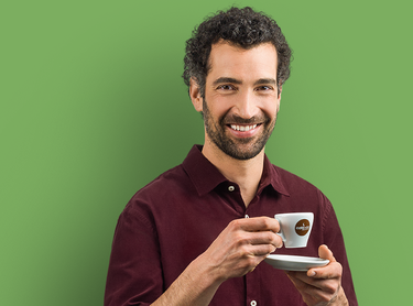 Lächelnder Mann hält eine Tasse Espresso mit Untertasse