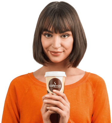 Eine lächelnde Frau hält einen Kaffeebecher mit beiden Händen