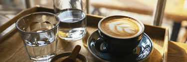 Tablett mit Cappuccino und zwei Gläsern Wasser