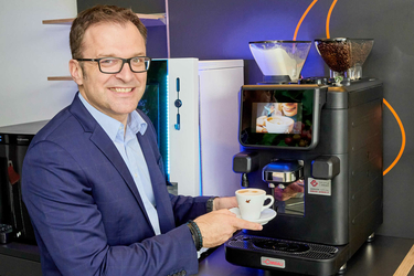Fritz Kaltenegger mit Kaffeetasse vor einem Kaffeeautomaten